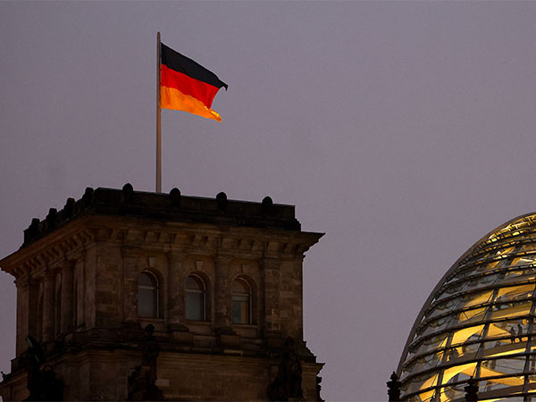 German national flag flying atop the illuminated Reichstag building, the seat of the Bundestag, Germany's lower house of parliament, in Berlin (Source: Reuters)