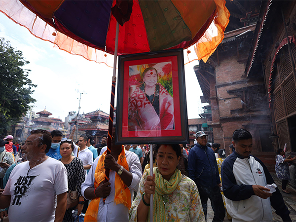 A woman holds a framed photo of a departed loved one under a colorful umbrella during the Gai Jatra festival procession in Basantapur Durbar Square, Kathmandu, as people pay tribute to those who passed away in the past year (Photo/ANI)