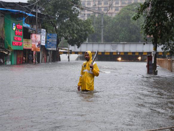 A man stands amid a flooded road near a closed subway following heavy rainfall (File Photo/ANI)