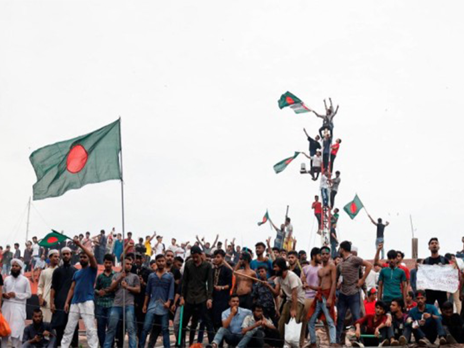 People wave Bangladeshi flags atop Ganabhaban, the Prime Minister's residence, during celebrations following the resignation of PM Sheikh Hasina, in Dhaka (File Photo//Reuters)