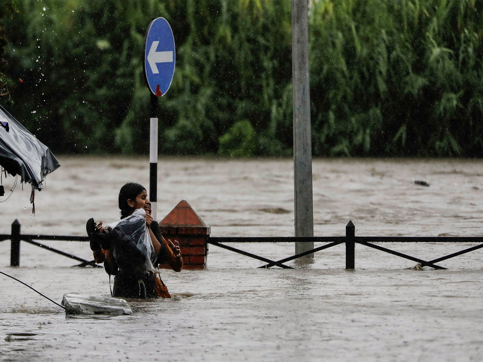 A woman wades through a flooded road along the overflowing Bagmati River carrying her belongings after heavy rains in Kathmandu, Nepal (File Photo/Reuters)
