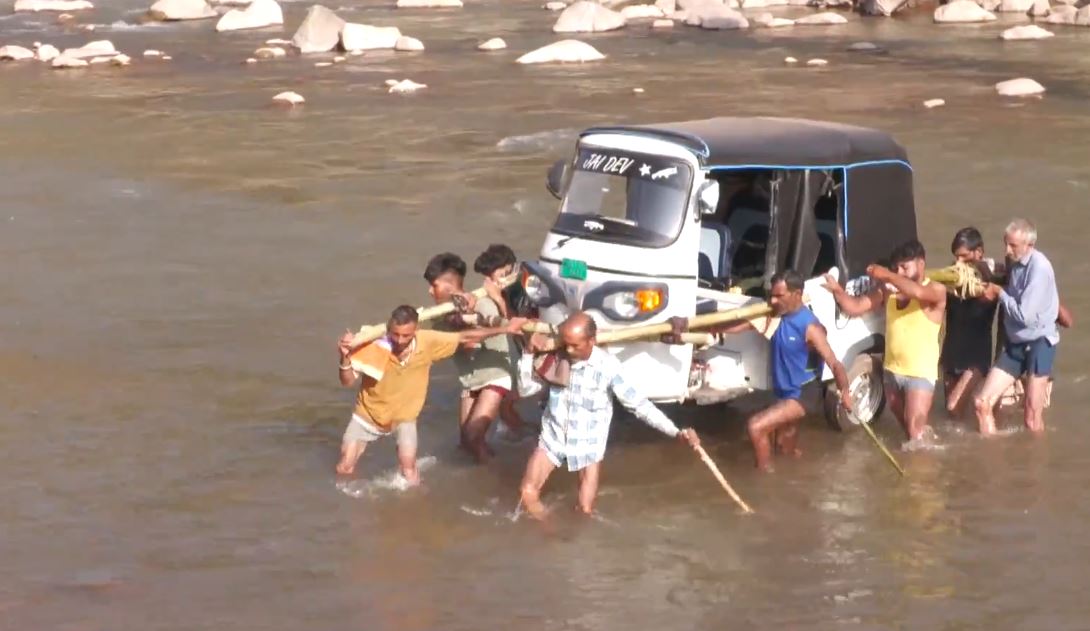 Villagers from Bant Village of Jammu and Kashmir's Udhampur district carried an Auto Rickshaw on their shoulders to cross a river, after heavy rains washed away a key bridge in recent times. (Photo/ANI)