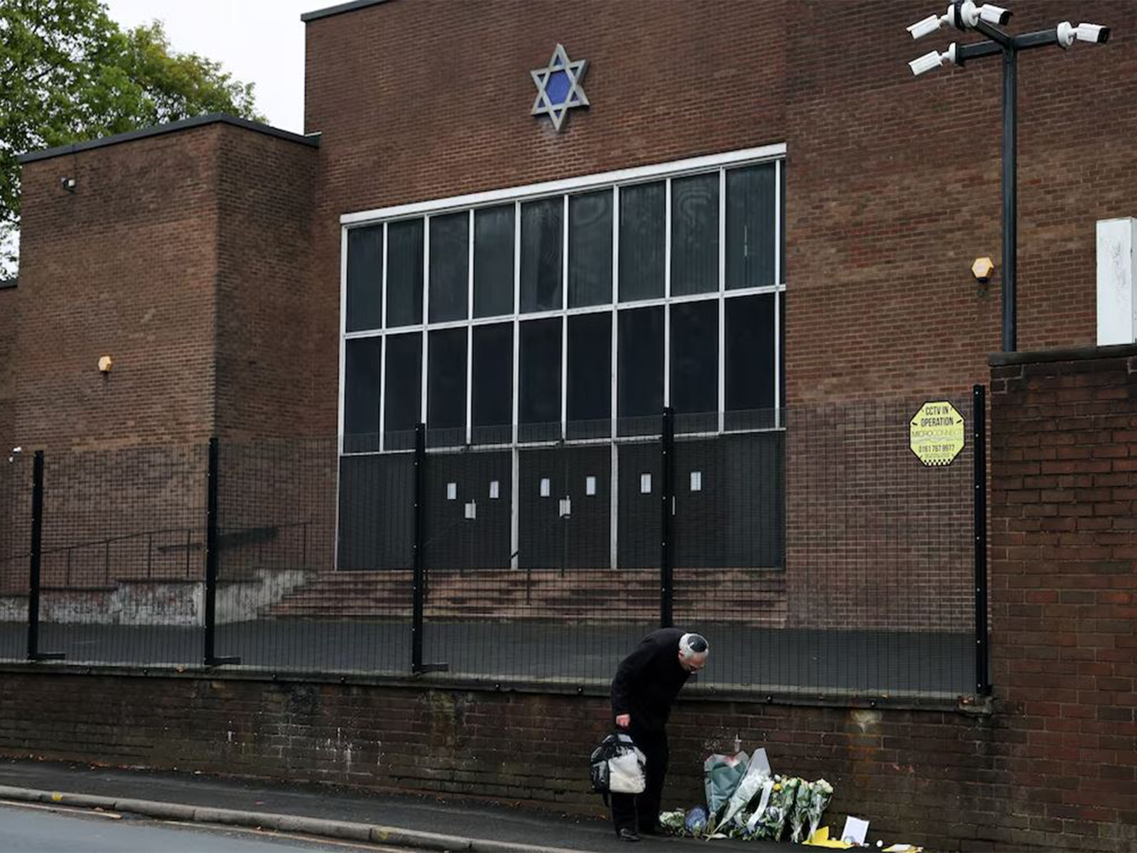 A man looks at floral tributes outside the Manchester synagogue, where multiple people were killed on Yom Kippur (Photo/Reuters)