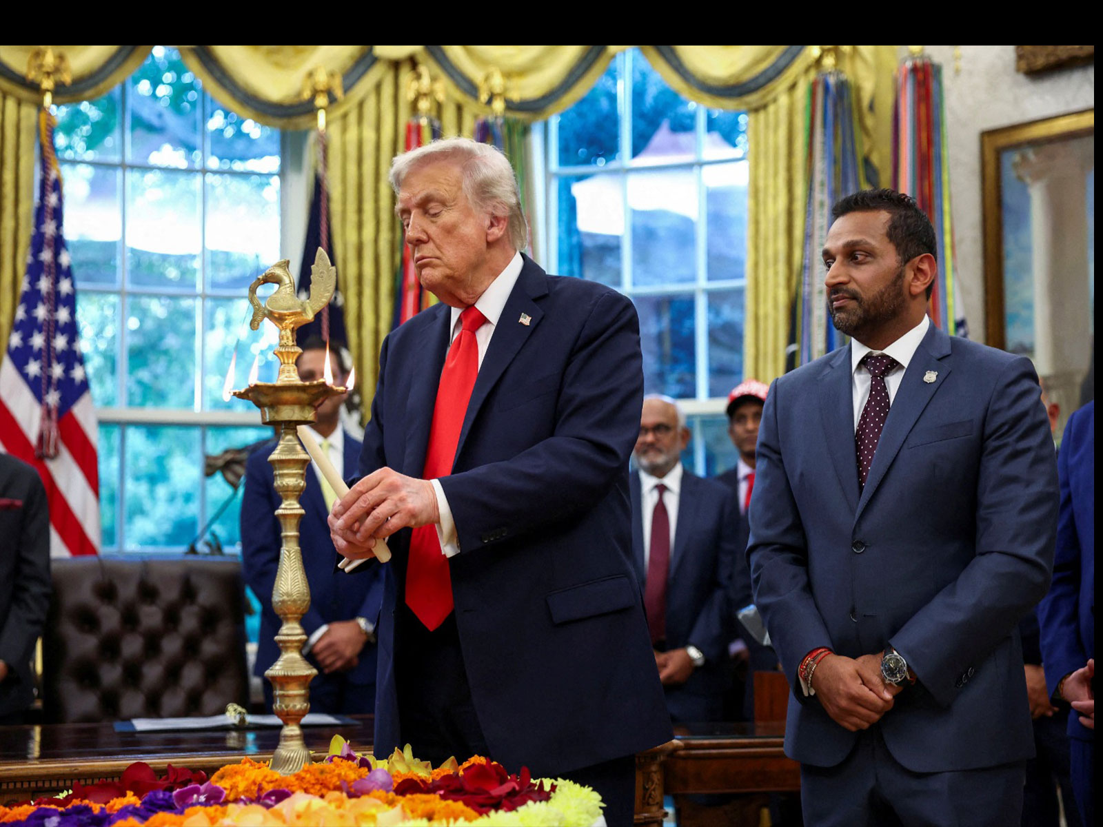 US President Donald Trump lights a candle as he participates in a Diwali celebration at the White House alongside FBI Director Kash Patel (Photo/Reuters)