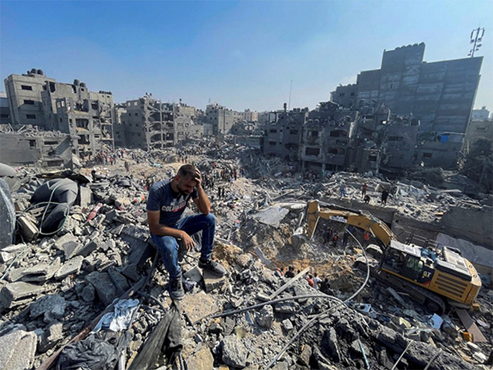 A man sits amid the rubble of destroyed buildings in Gaza following Israeli airstrikes (File Photo/ Reuters)