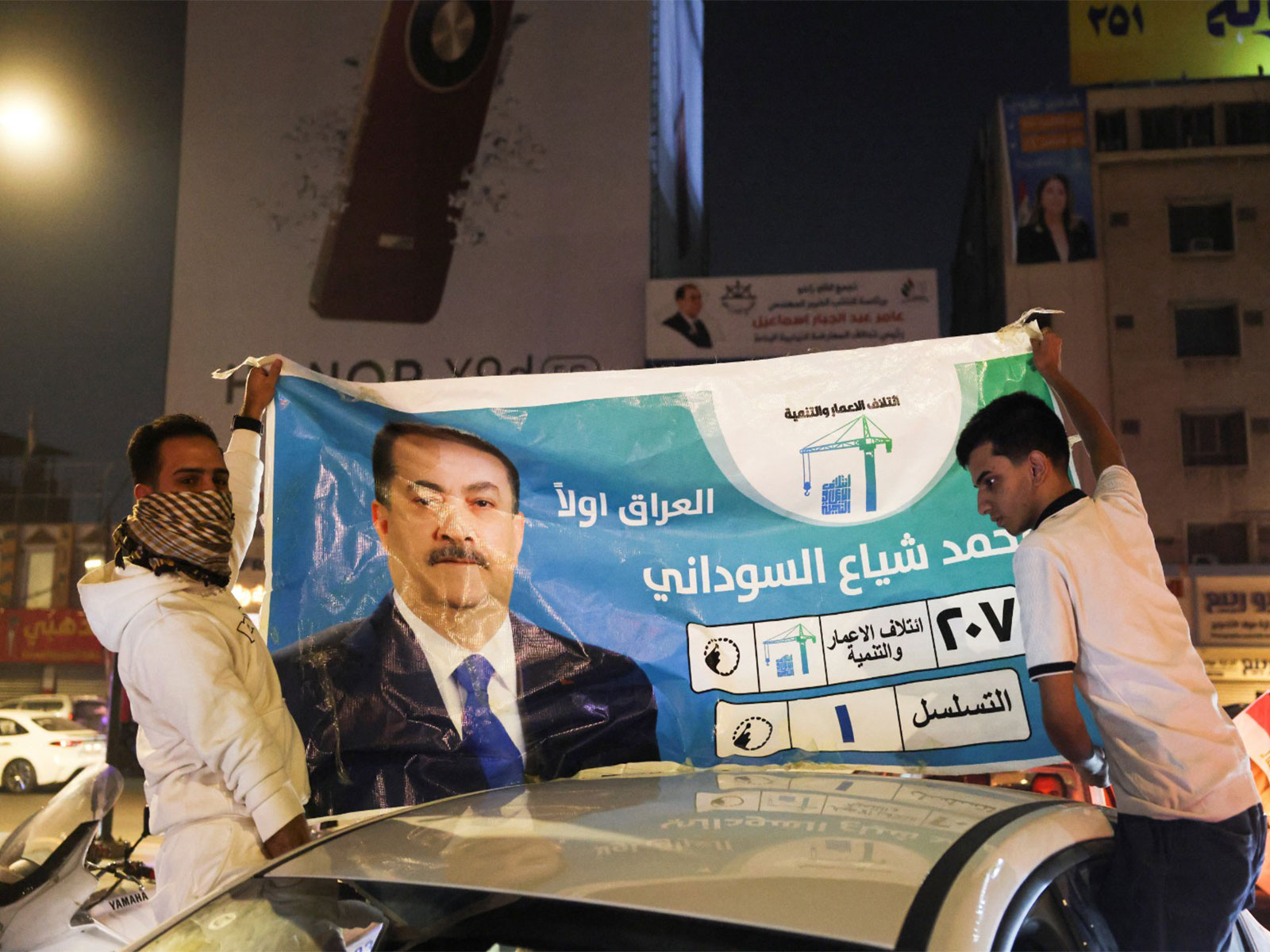 People hold an election poster featuring current Prime Minister Mohammed Shia' al-Sudani on top of a car (Photo/Reuters)