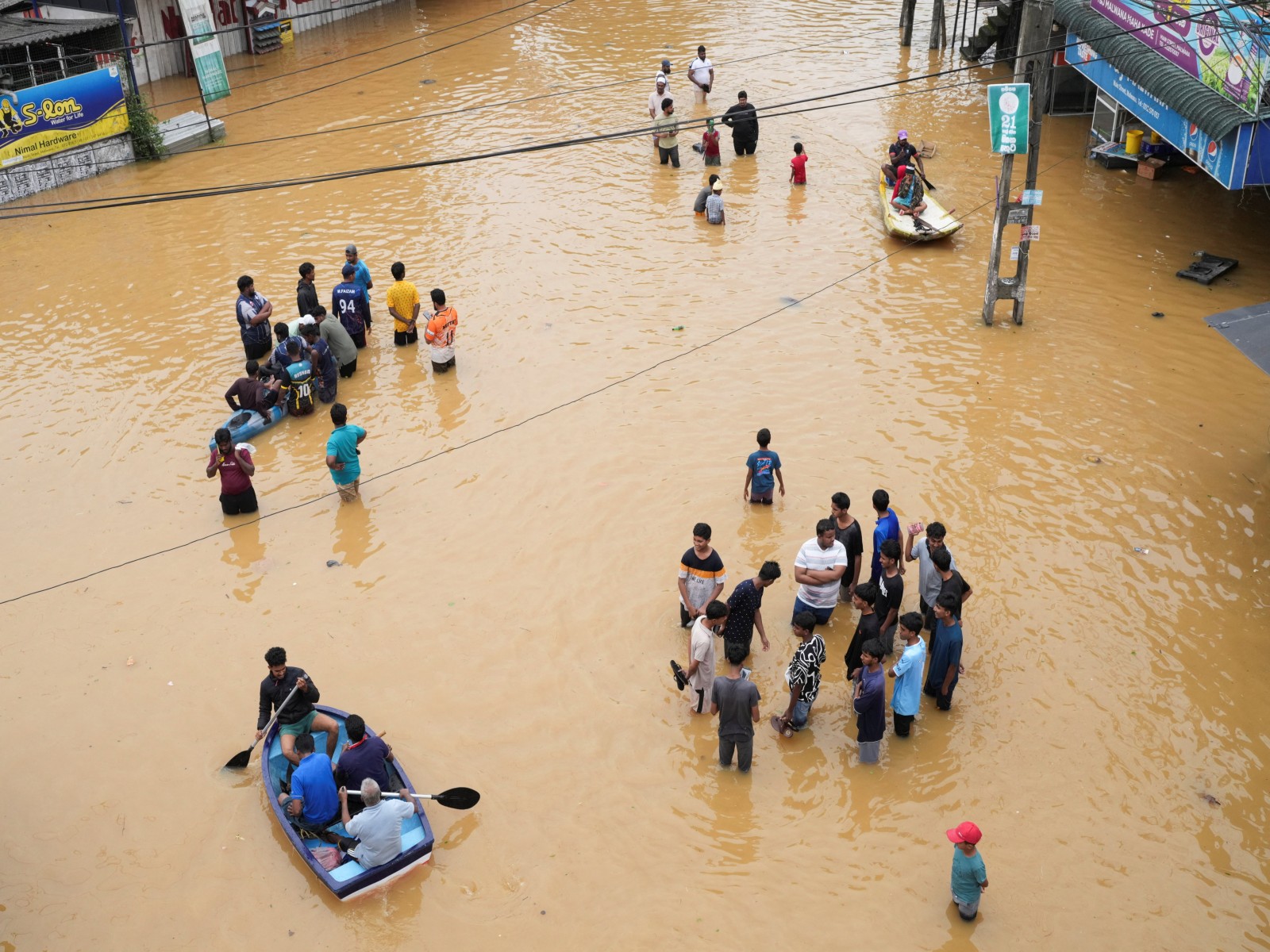 People use boats to move on a flooded street as others stand around, following heavy rainfall in Malwana, Sri Lanka (Photo/Reuters)