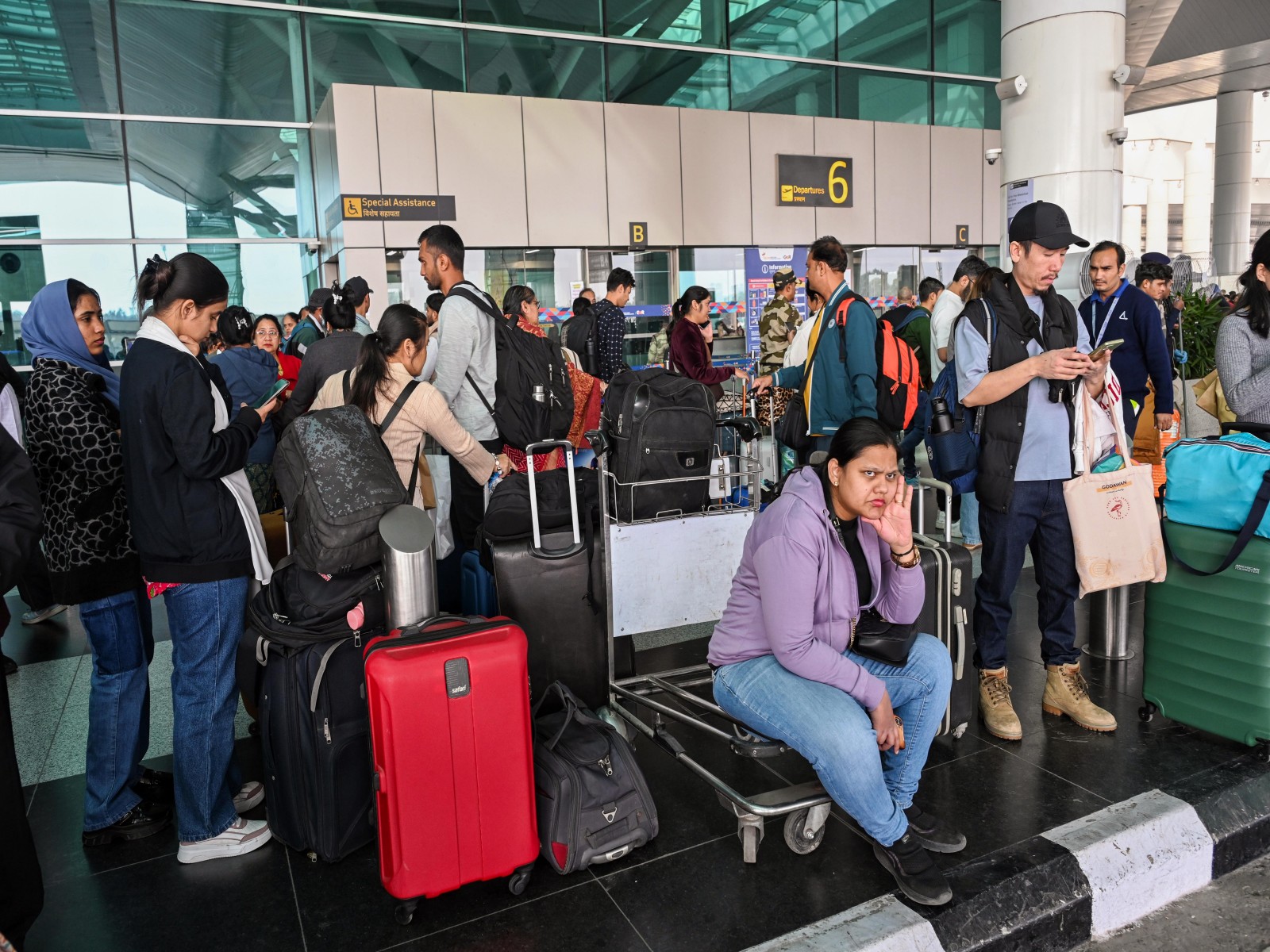 Flight passengers wait with their baggage as many IndiGo flight services stand cancelled in Delhi Airport (Photo/ANI)