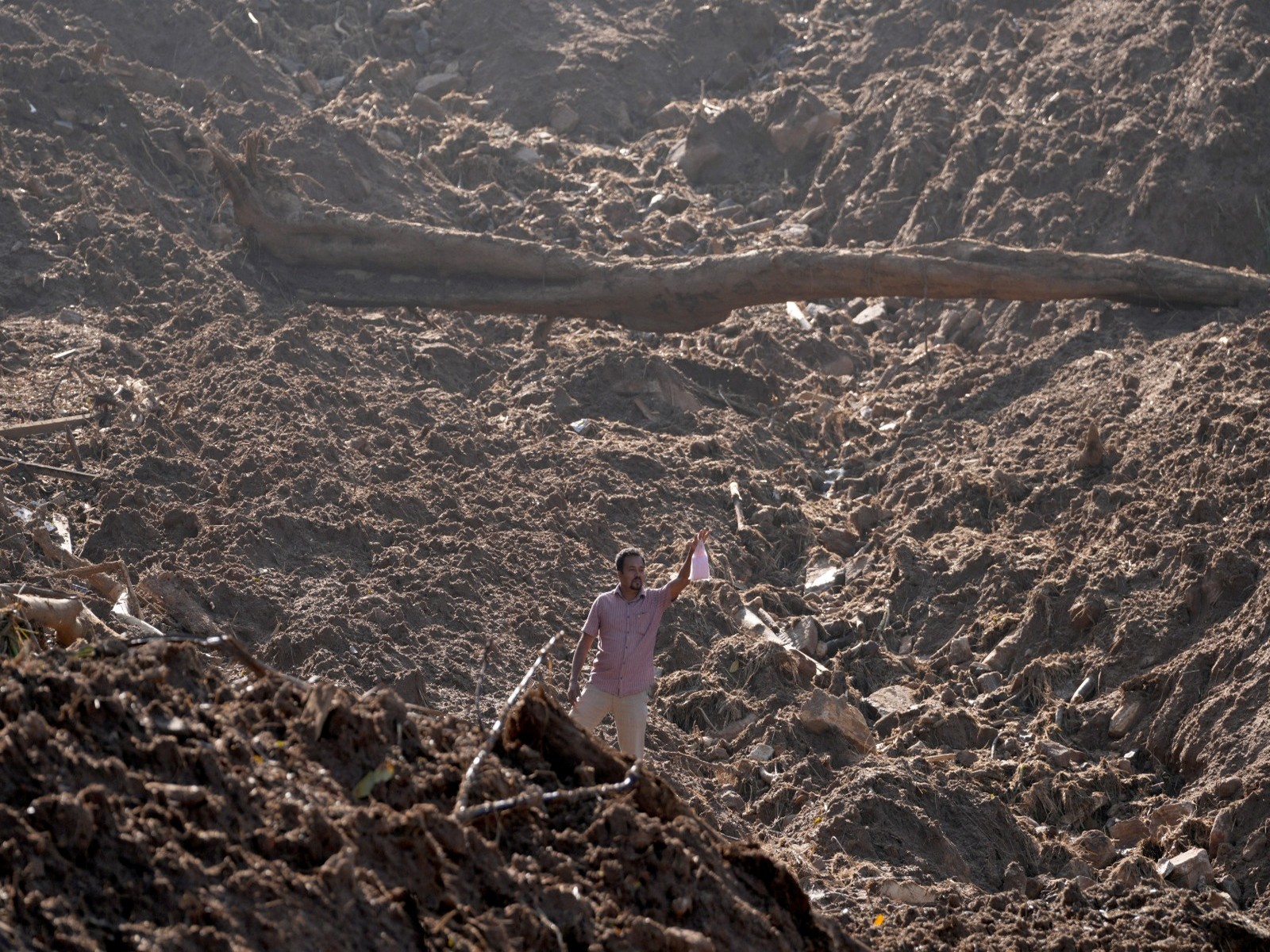 A man holds up a food packet as he moves through mud after landslides triggered by heavy rainfall following Cyclone Ditwah in Sri Lanka (Photo/Reuters)