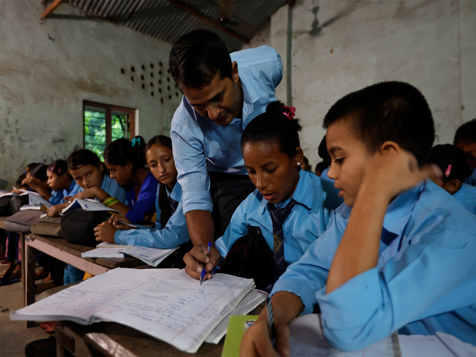 A teacher assists students during a class at a government school in Nepal, highlighting everyday classroom learning amid broader reforms in the country's education assessment system. (Photo/Reuters)