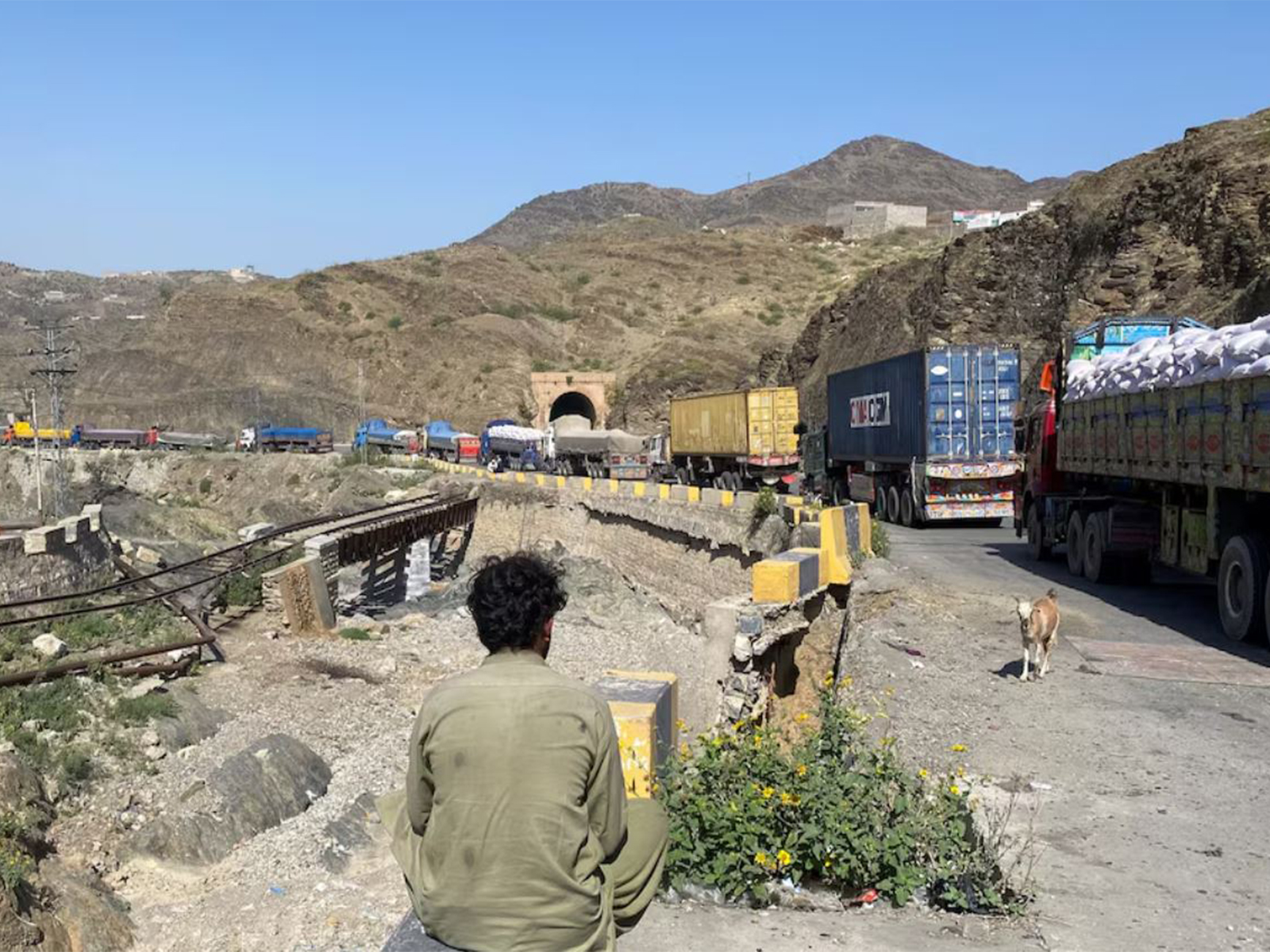 A man sits next to trucks parked at the Torkham border crossing, after Pakistan closed border crossings with Afghanistan, following exchanges of fire between the forces of the two countries, in Torkham (File Photo/Reuters)