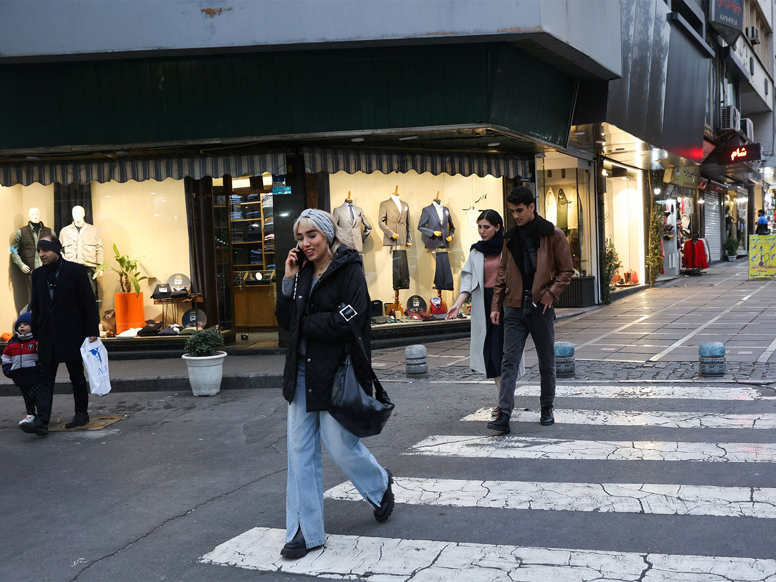 People walk on a street as protests erupt over the collapse of the currency's value in Tehran (Photo/Reuters)