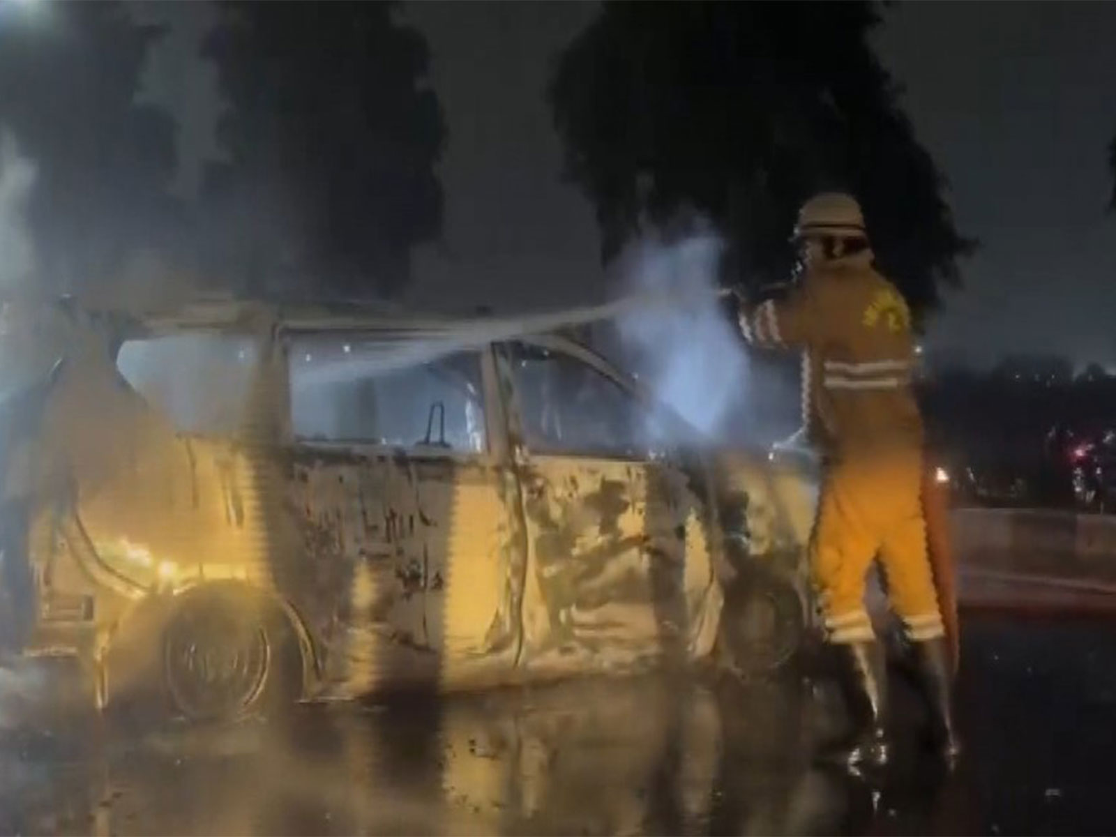 A firefighter trying to douse the fire in the car in Noida. (Photo/ANI)