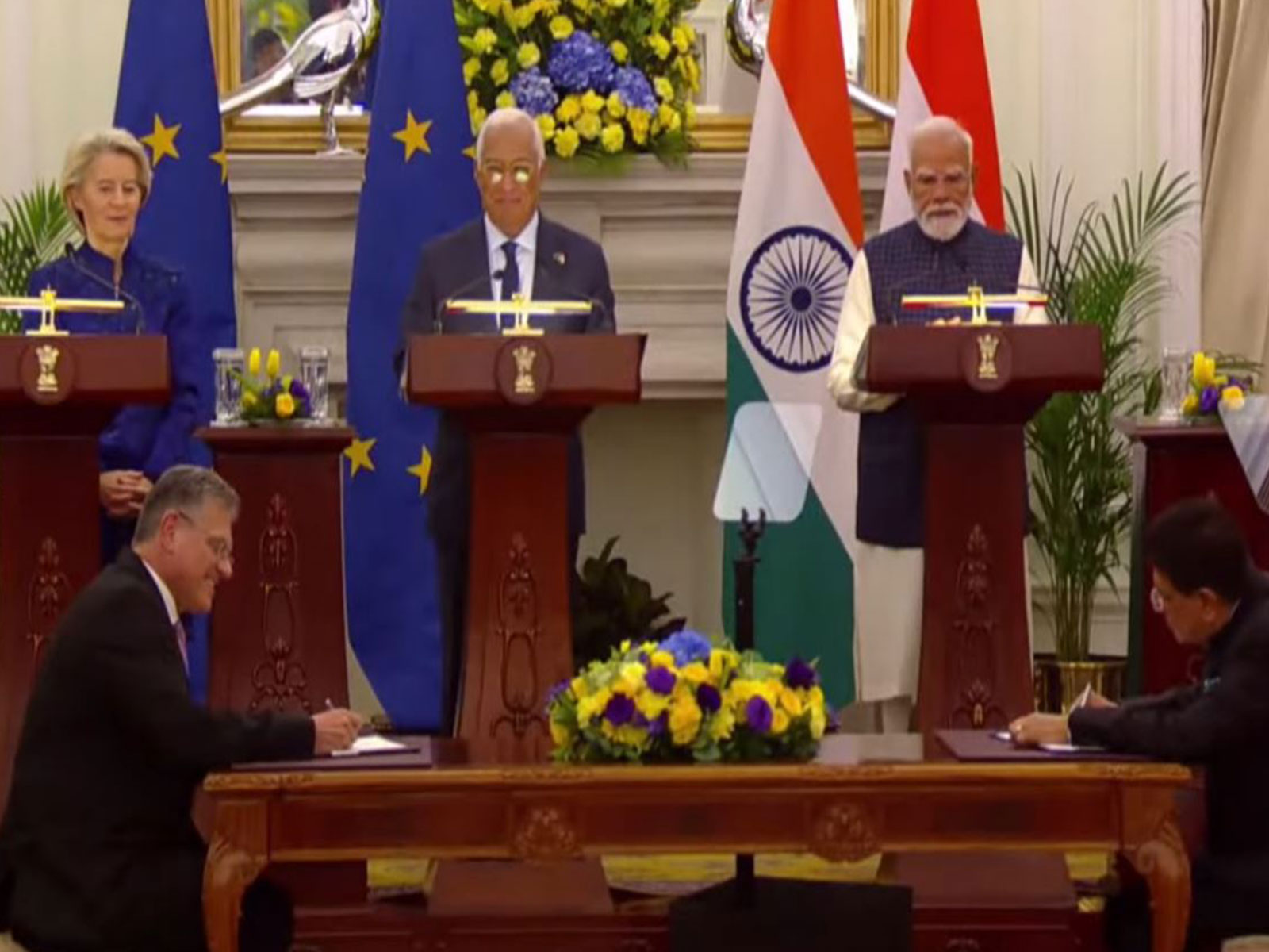 EU Trade Commissioner Maros Sefcovic and Union Commerce Minister exchange documents on conclusion of India-EU FTA as PM Modi, President of EU Commission Ursula von der Leyen and President of EU Council Antonio Costa look on (Photo/MEA)