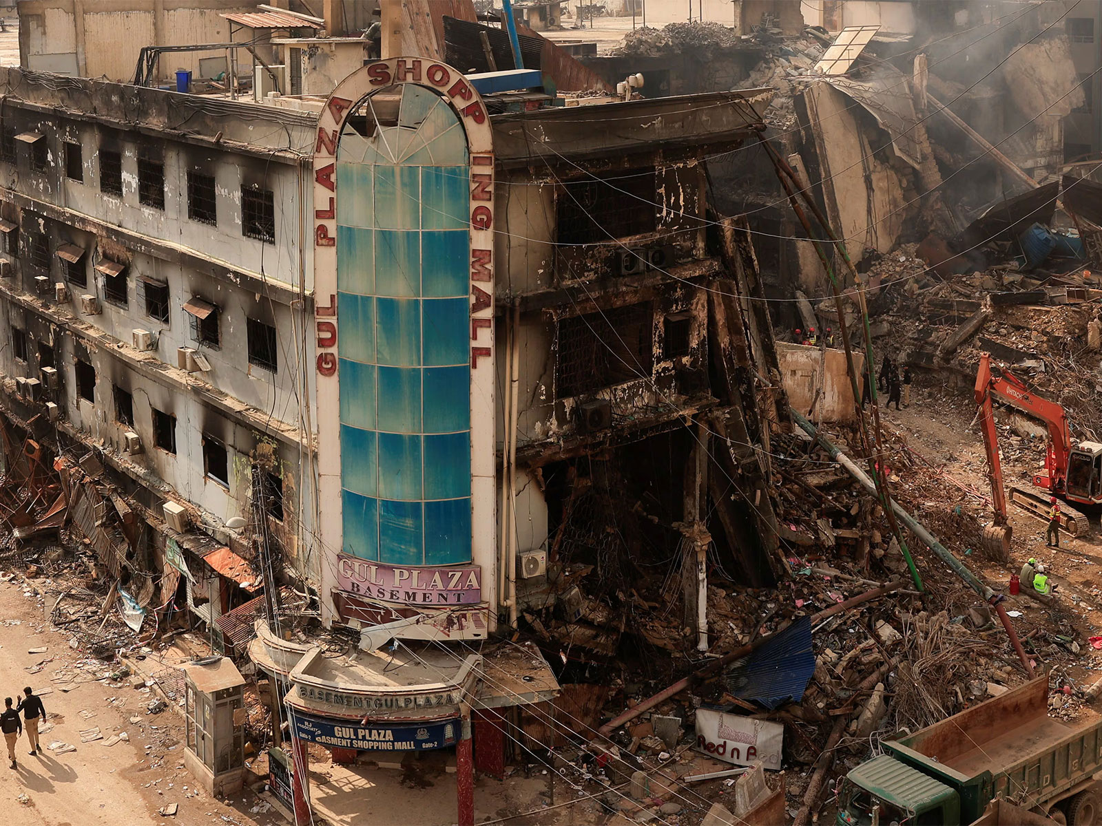 Police personnel walk past the site of a massive fire at Gul Plaza Shopping Mall in Karachi, Pakistan. (Photo/Reuters)