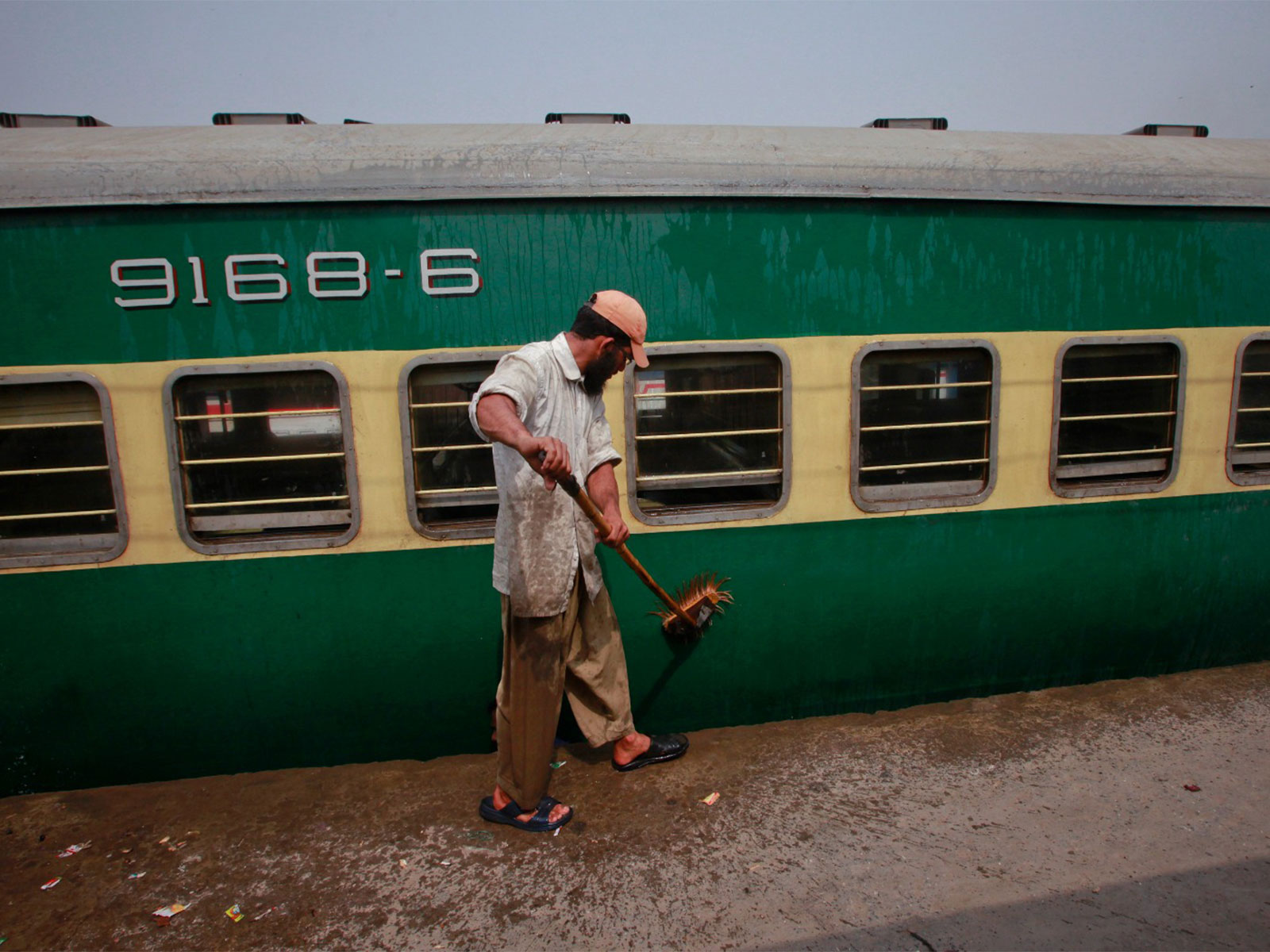 A man washes a passenger train carriage parked in a railway station yard in Lahore (File Photo/Reuters) 