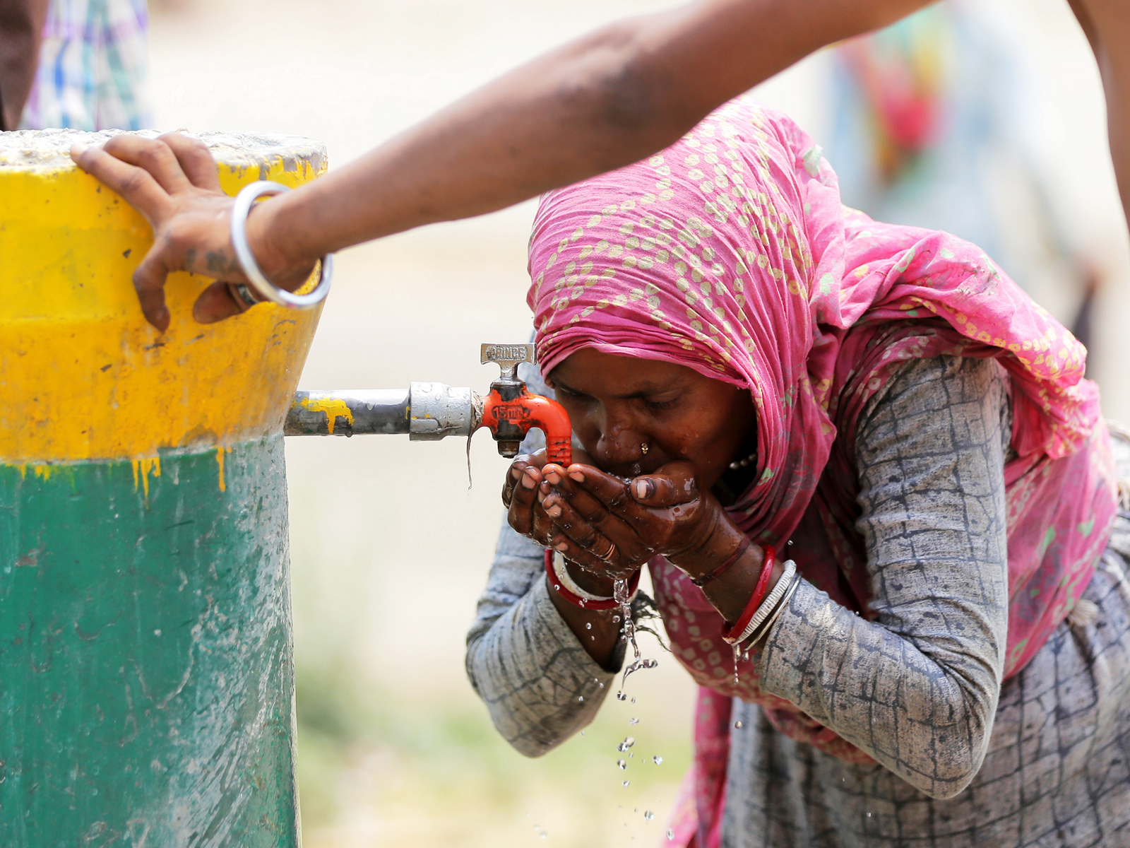 A woman drinking water from a public tap (Photo/ANI)