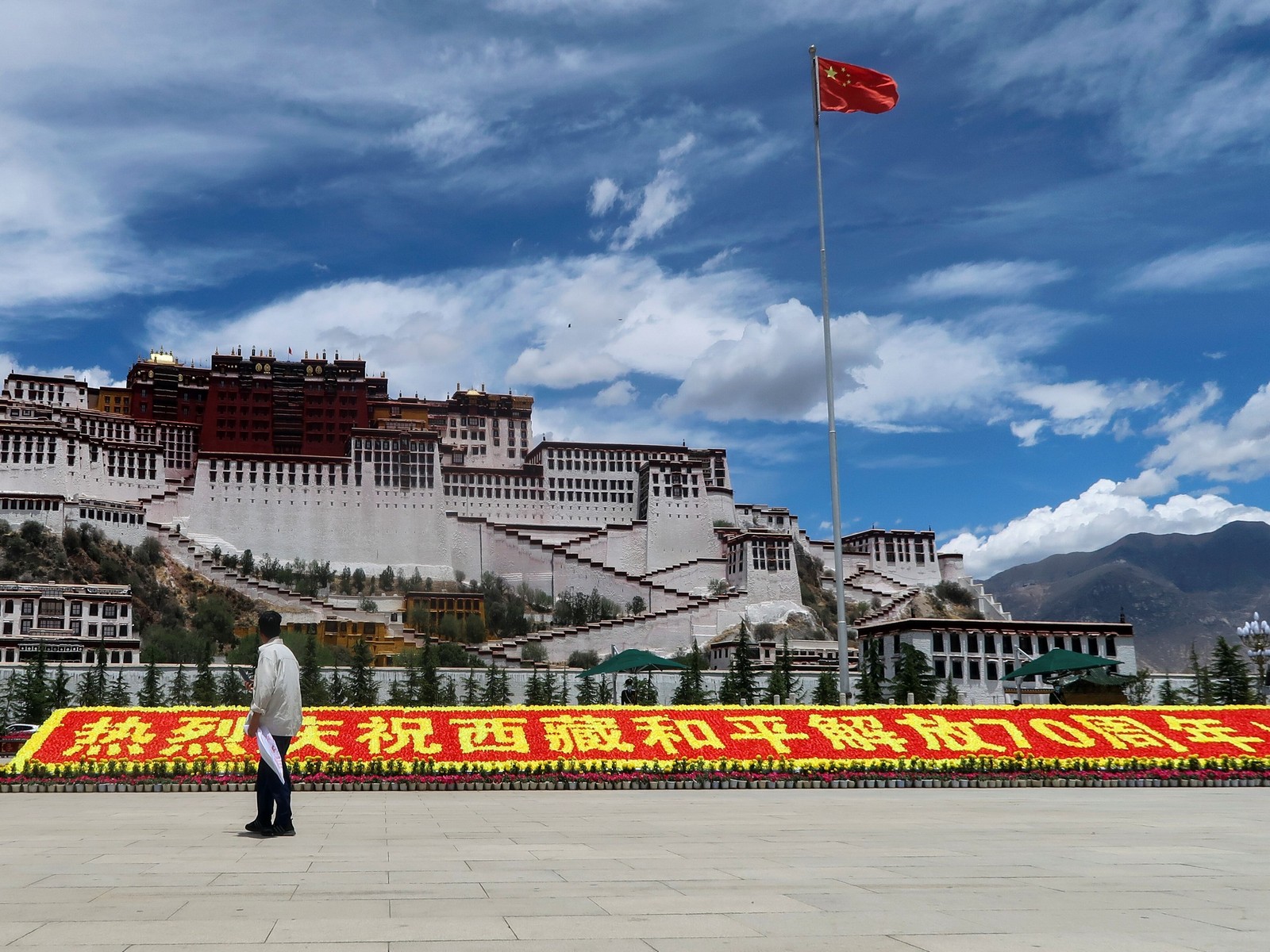 A man stands near a sign marking 70 years of Chinese rule over the Tibet Autonomous Region at Potala Palace Square during a government-organised media tour in Lhasa, China. (Photo/Reuters)
