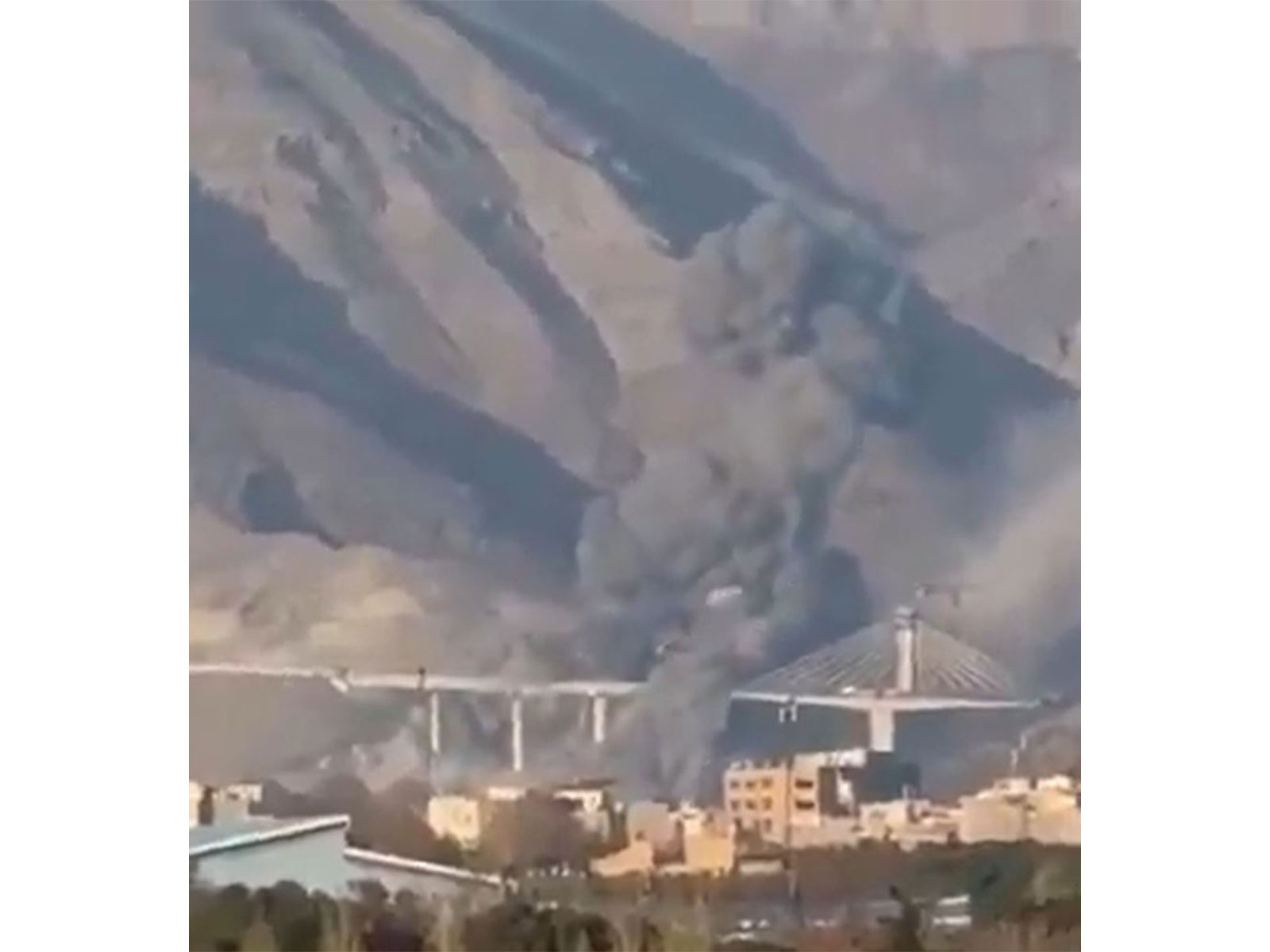 Smoke rises near Karaj's B1 bridge following reported strikes that caused civilian casualties and damage in the surrounding area. (Image Source: Iranian state media)