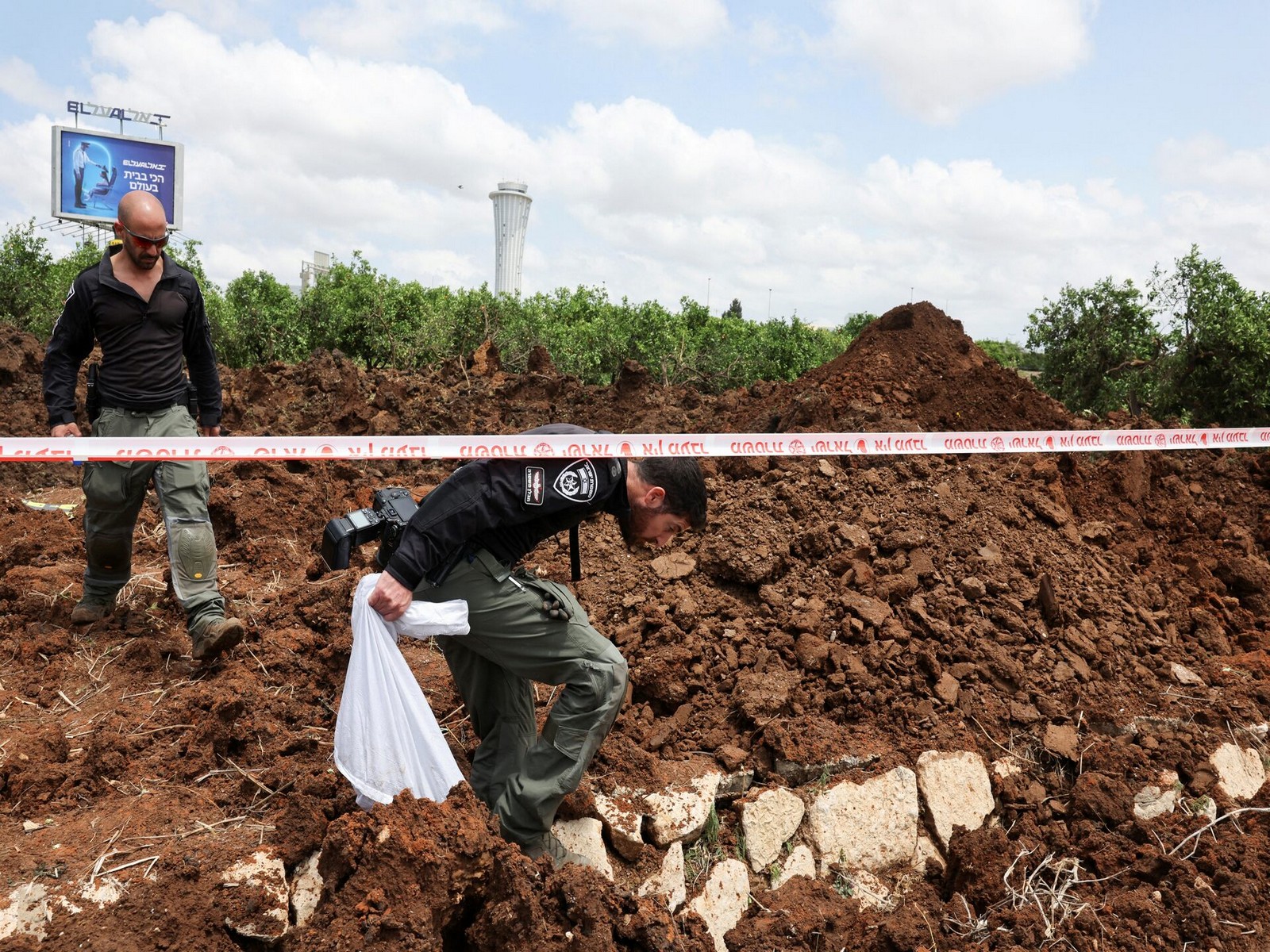 Following a missile launch from Yemen, Israeli police officers examine an impact crater near Tel Aviv's Ben Gurion Airport. (Photo/Reuters)