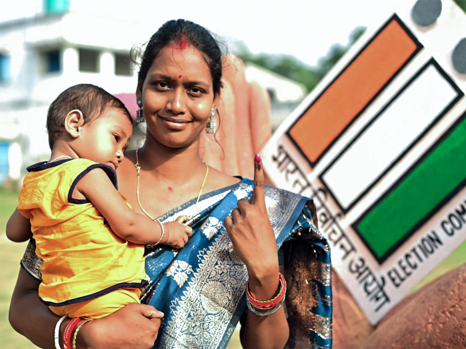 A woman carrying a child shows her inked finger after casting her vote in West Bengal's Jhargram (File Photo/ANI)