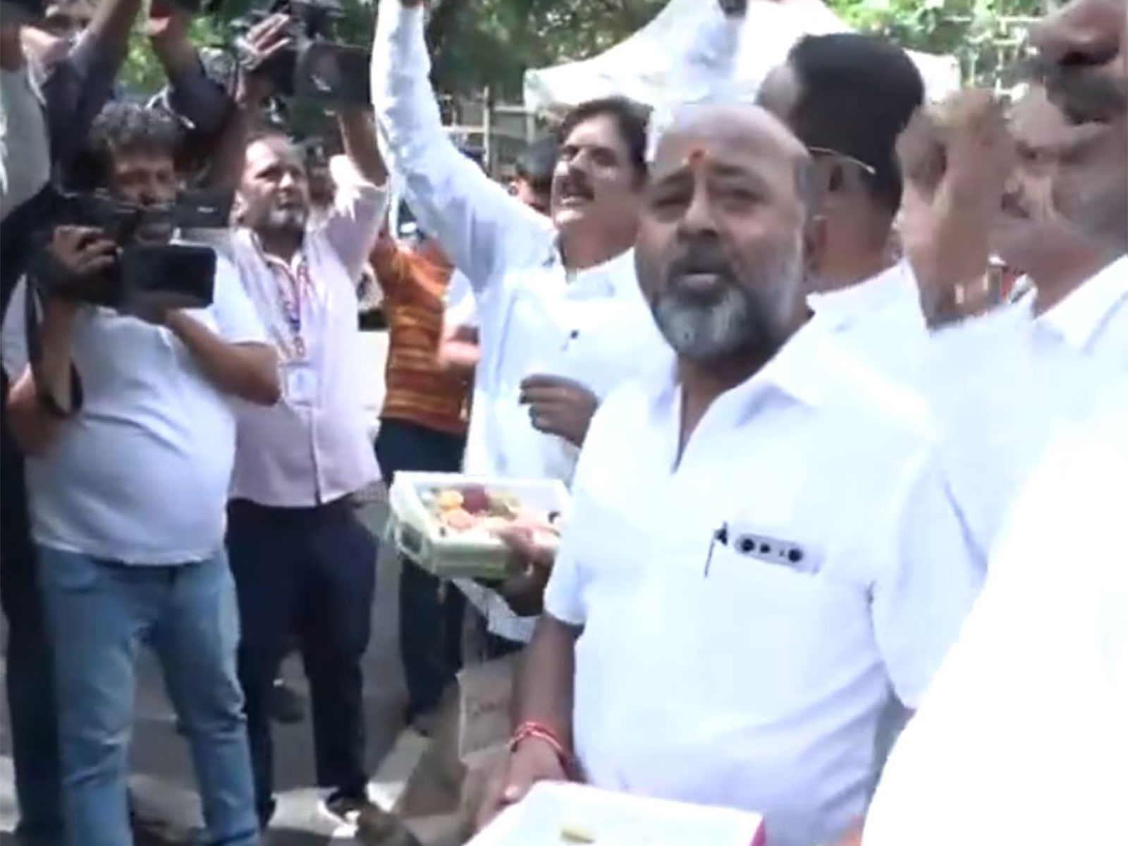 Supporters of Karnataka Deputy Chief Minister DK Shivakumar distribute sweets outside his residence (Photo/ANI)