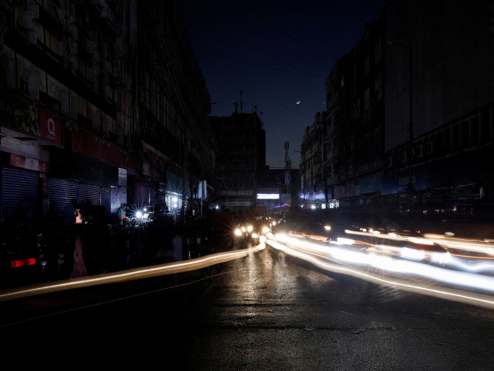 Vehicle headlights create light trails along a market road during a widespread power outage in Pakistan. (Photo/Reuters)