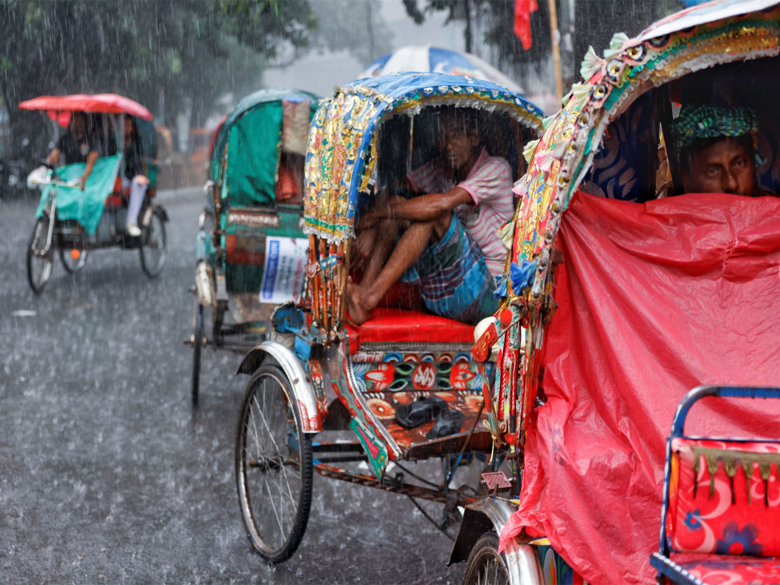 Rickshaw drivers sit inside of their rickshaws to take cover during torrential rain in Dhaka, Bangladesh (Photo/Reuters)
