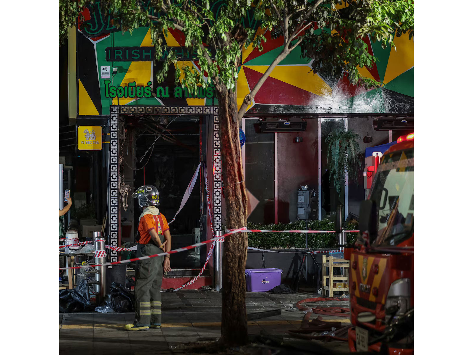 Firefighters and emergency personnel stand outside the fire-ravaged Na Ladprao eatery in Bangkok's Chatuchak district after a deadly blaze killed at least 27 people and injured dozens in the early hours of Monday. (Photo/Reuters)