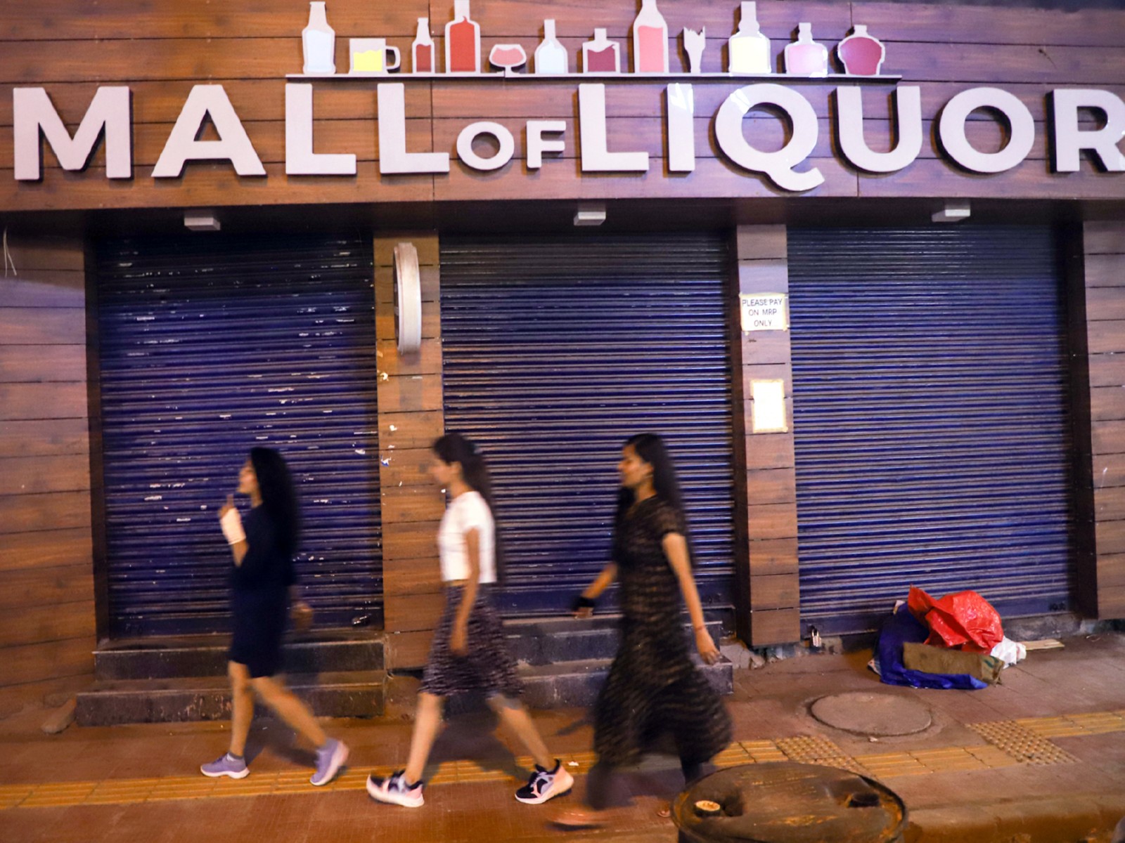 People walk past a closed liquor shop at GTB Nagar (File Photo/ANI)
