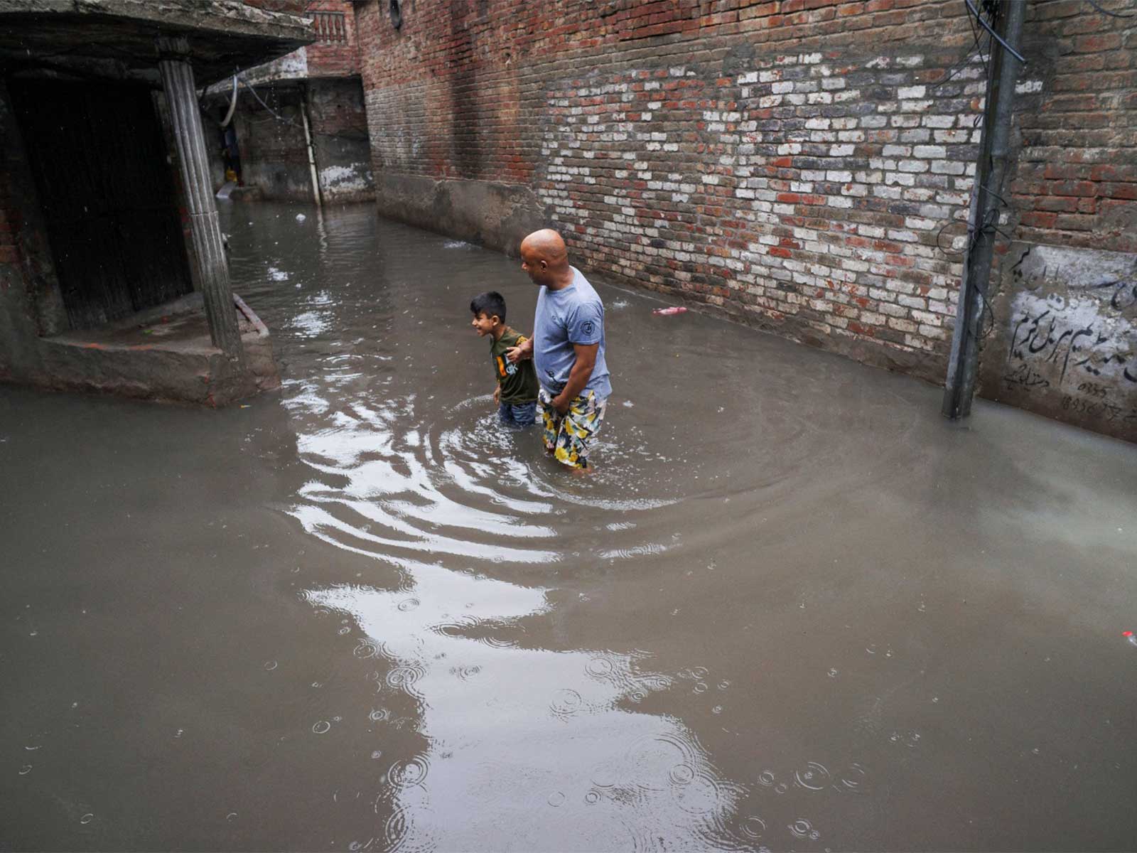 A man and a boy wade through a flooded street amid rain in Gujranwala, Pakistan (Photo/Reuters)