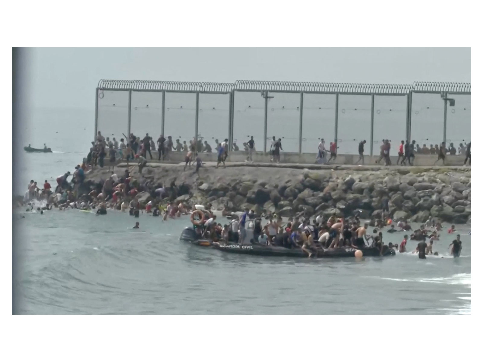 Migrants gather on and around a Guardia Civil boat as they swim through Spain's Ceuta border from the Moroccan side (Photo/ANI)