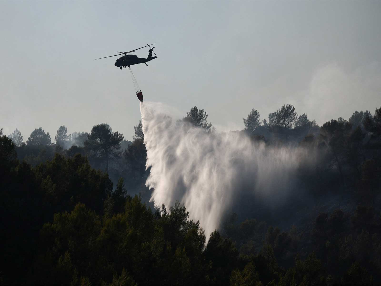 A firefighting helicopter drops water during a wildfire near Montfort-sur-Argens, near Correns, in the Var department, as drought conditions worsen following a heatwave and water shortages across much of France (Photo/Reuters)