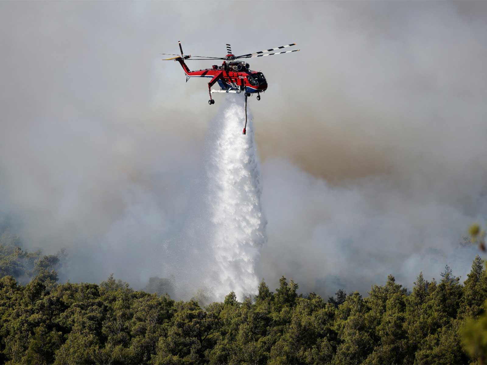 A helicopter drops water as a wildfire burns near the village Agios Nektarios, Greece (Photo/Reuters)