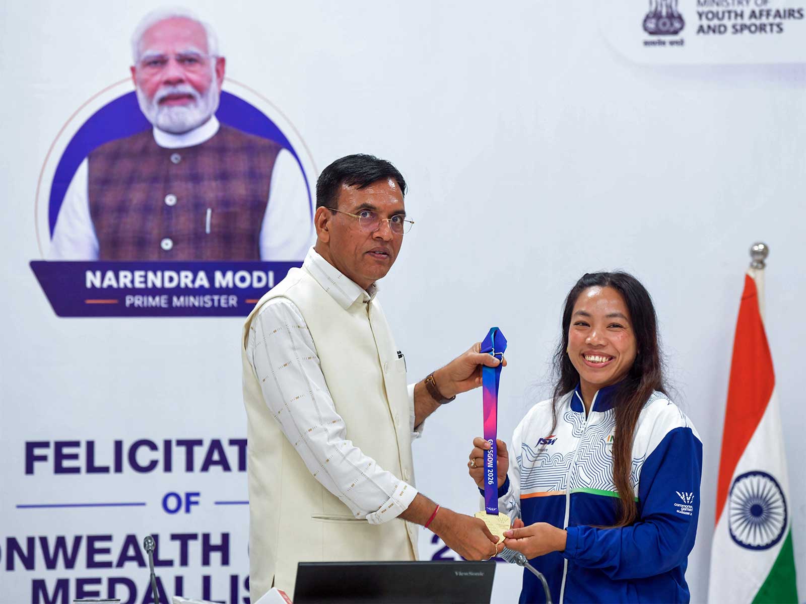 Mansukh Mandaviya felicitating women's 48kg gold medallist Mirabai Chanu during a ceremony honouring the weightlifting contingent for its performance at CWG 2026 (Photo: ANI)