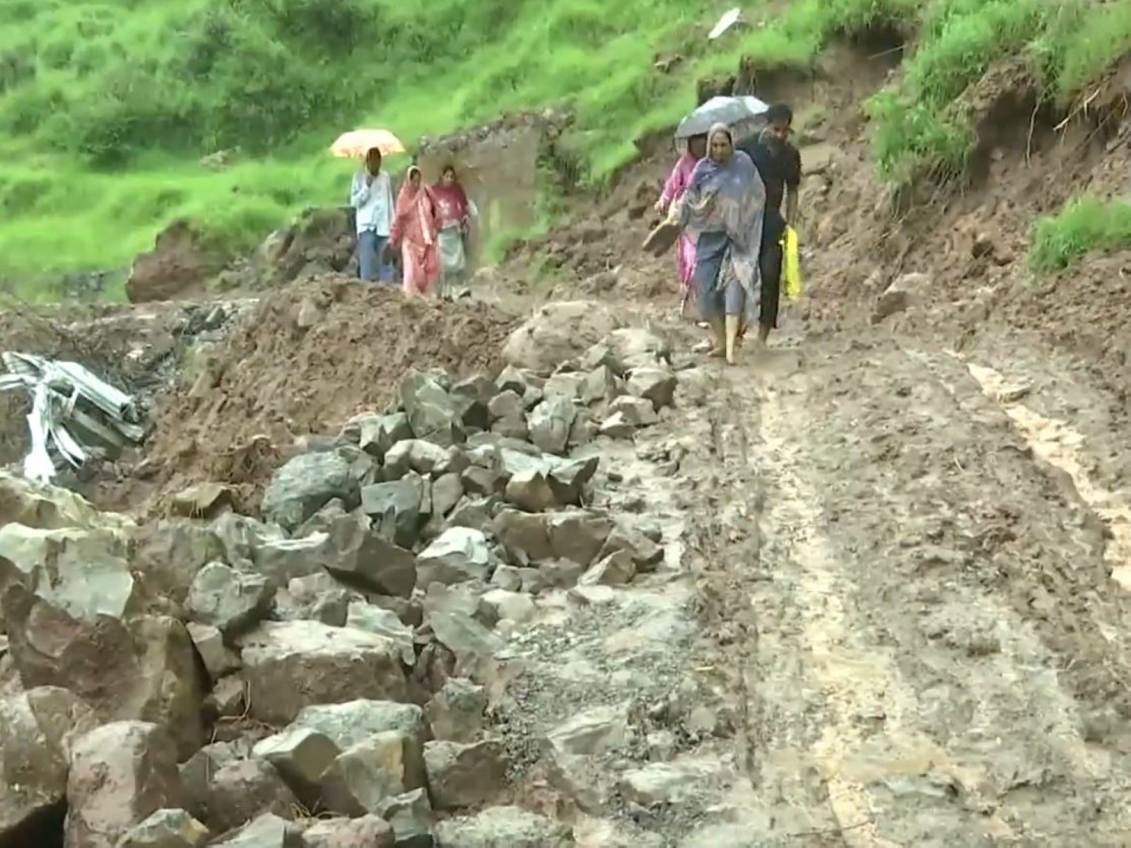 Locals slogging through a mudy road followinf rainfall in Rajouri, Jammu and Kashmir (Photo/ANI)