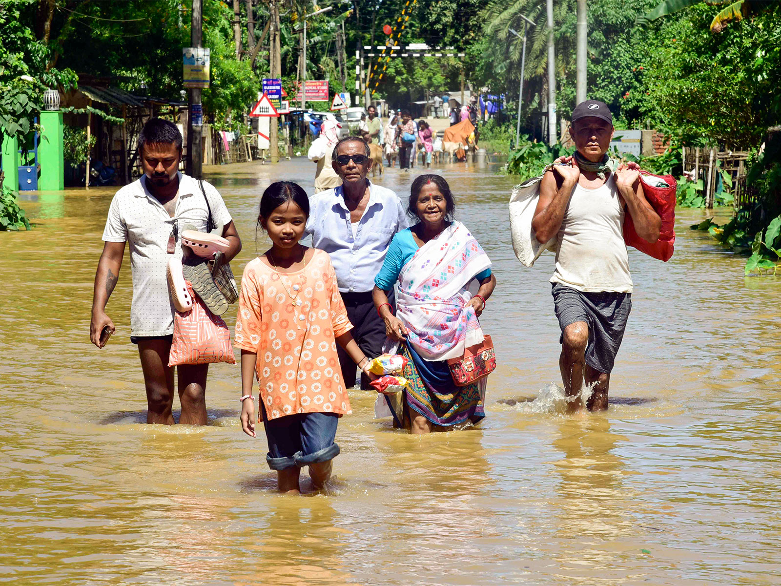 People moving to safer places carrying their belongings in a flood-affected area (File Photo/ANI)