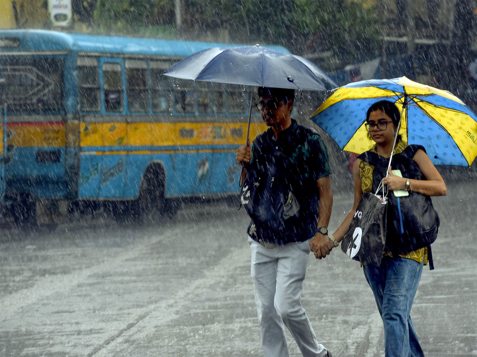 People walk under umbrellas amid heavy monsoon showers (File Photo/ANI)