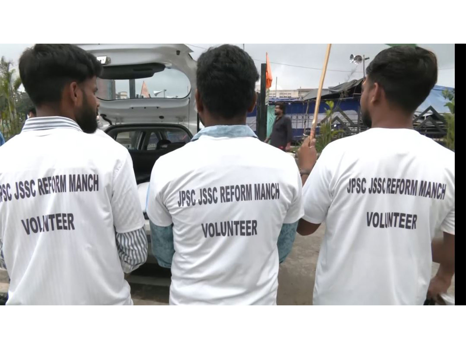 Volunteers wearing customized T-shirts printed with "JPSC JSSC REFORM MANCH VOLUNTEER" gather near a vehicle outside Jaipal Singh Munda Stadium in Ranchi (Photo/ANI)