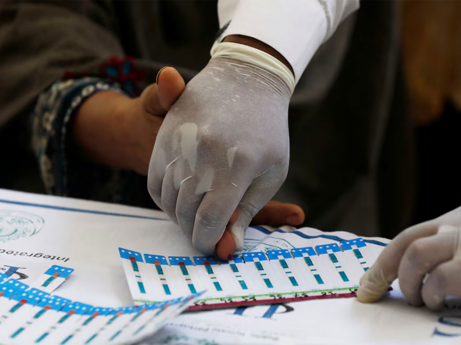A healthcare worker assists a woman with a blood sample collection for an HIV test at a free medical camp in Ratodero, Pakistan. (File Photo/Reuters)