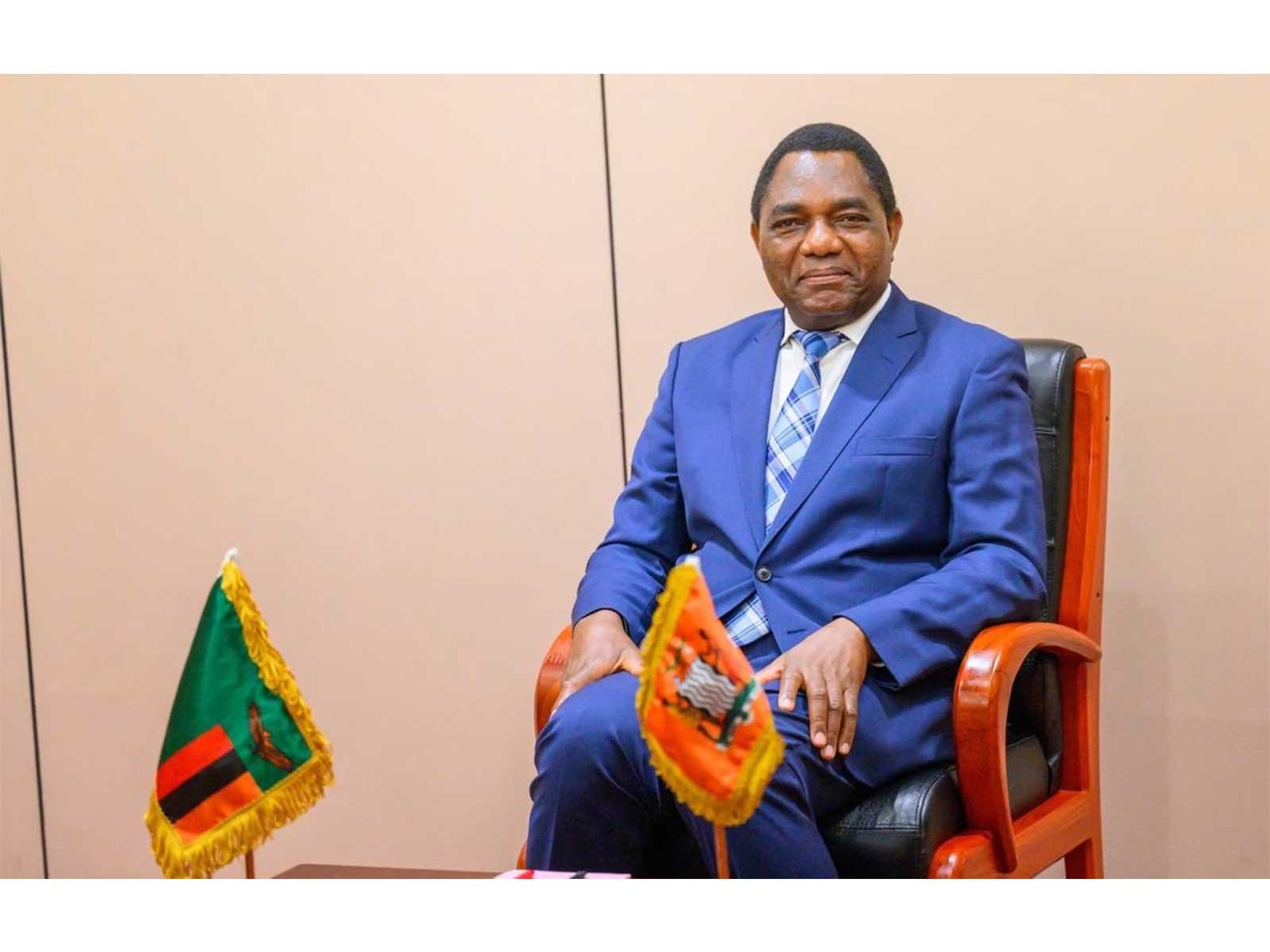 Zambian President Hakainde Hichilema seated in front of the Zambian national flags following his re-election victory. (Photo: X/@HHichilema)