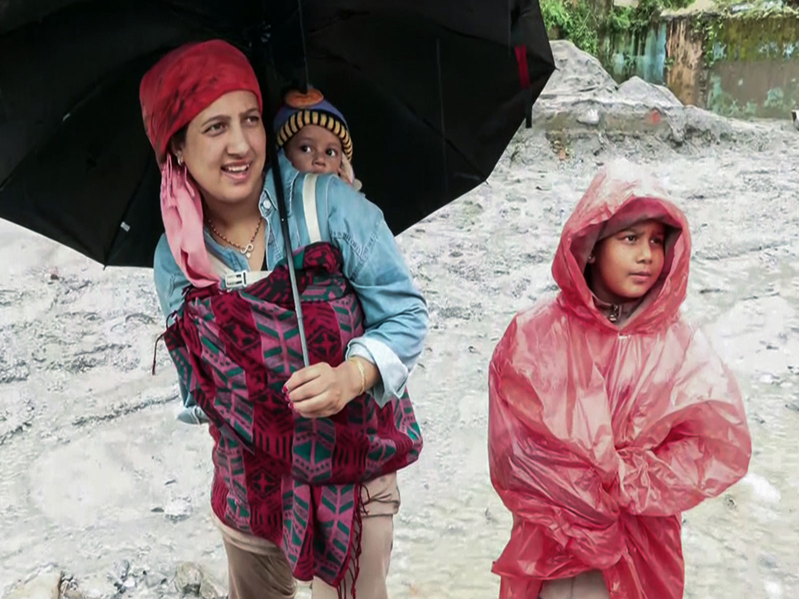 A mother carries one child on her back and another with her after flash-floods devastating Trishuli area (Photo/ANI)