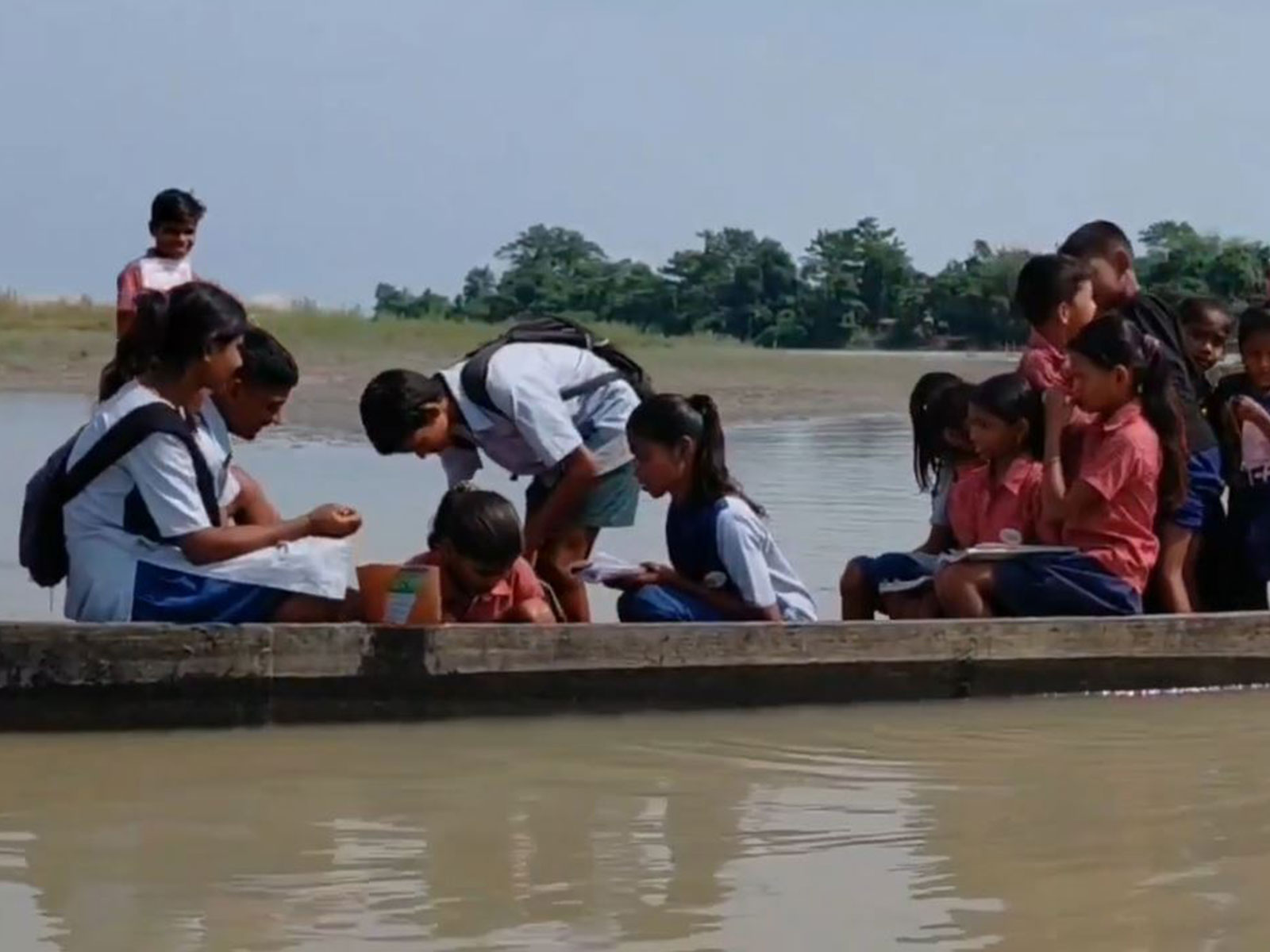 Schoolchildren cross the river by a small boat to reach school in Chengajan Gowala village of Dhemaji district, Assam. (Photo: ANI)