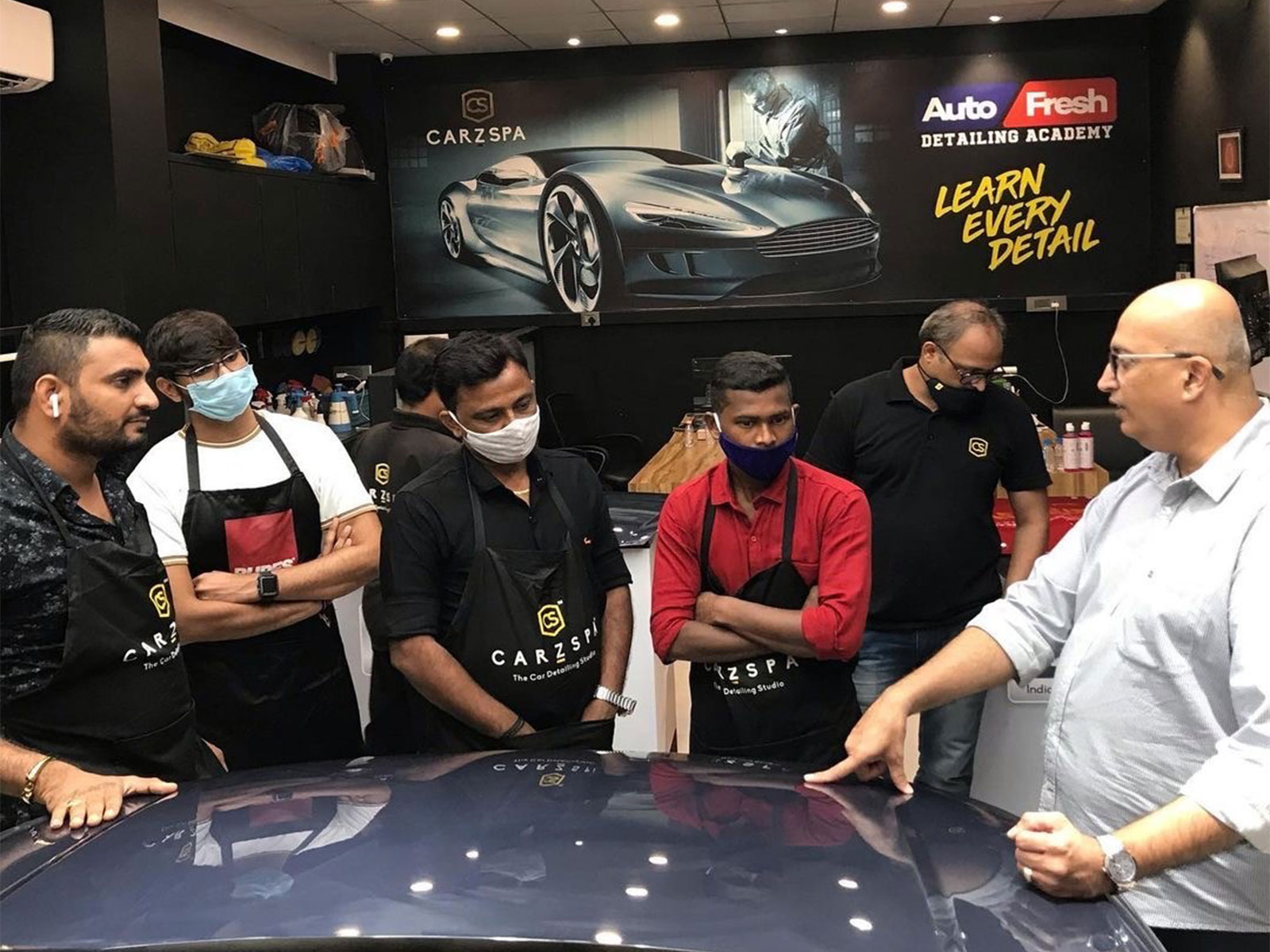 Professionals undergoing training inside a car detailing studio