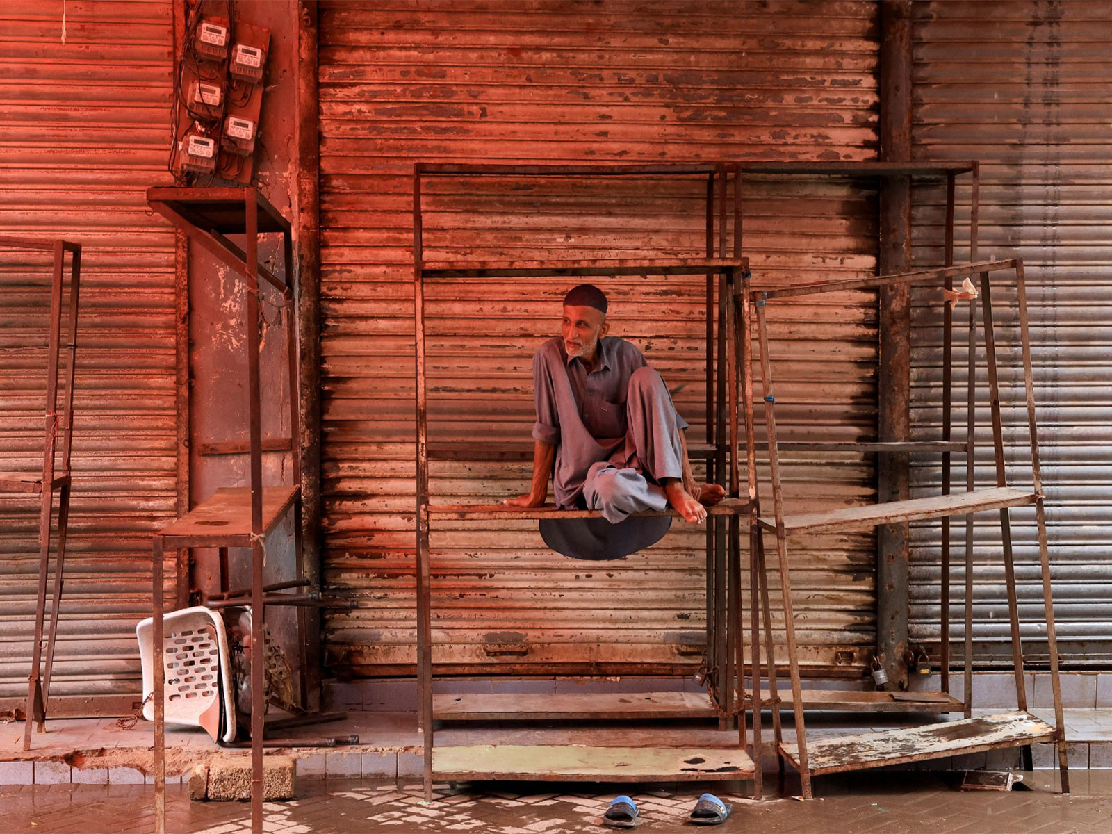 A salesman sits on iron frames outside closed shop in Pakistan (File Photo/Reuters)