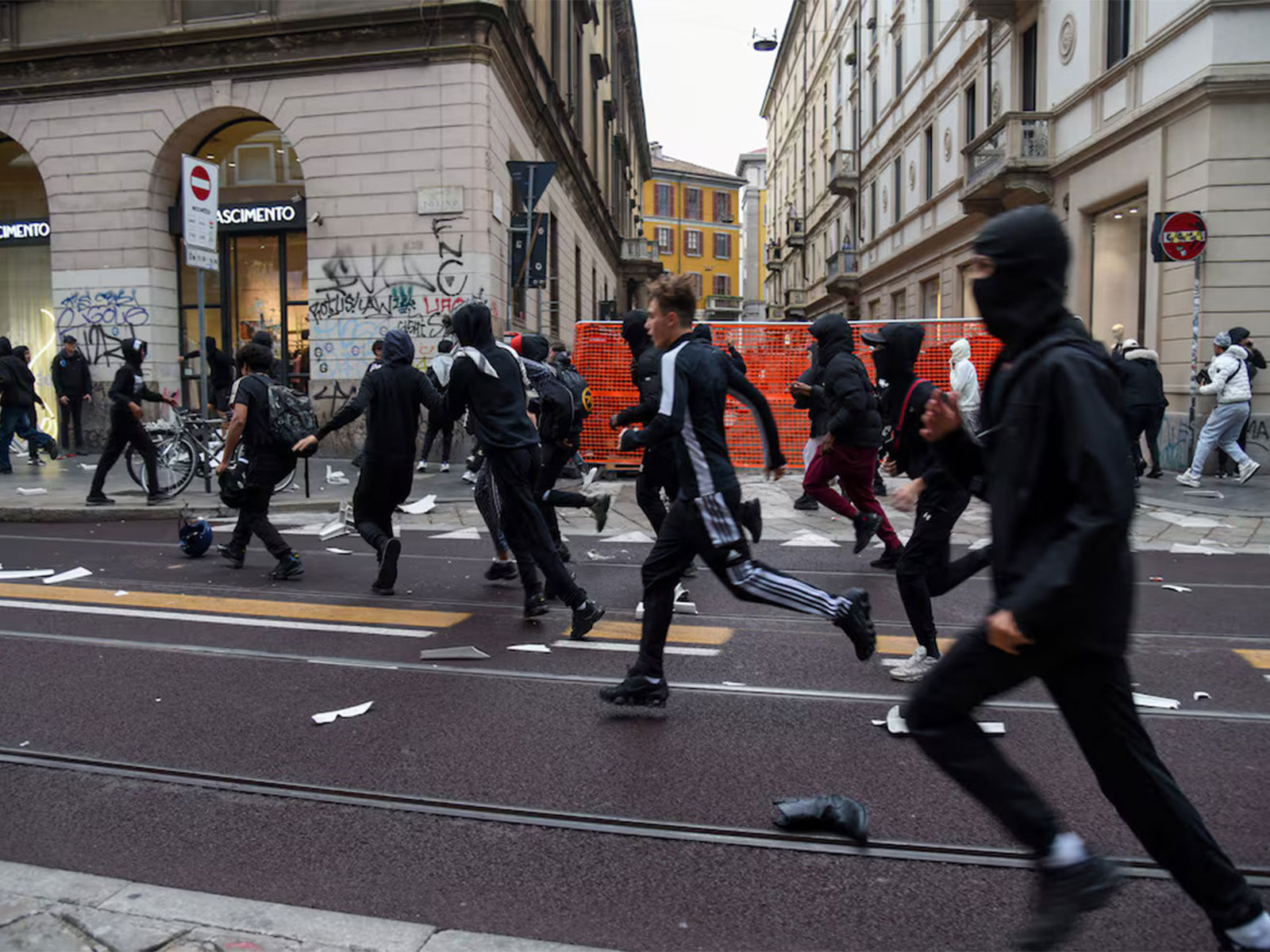 Protesters run along a street strewn with debris during a protest over the state of public services and the rising cost of living in Milan, Italy (Photo/Reuters)
