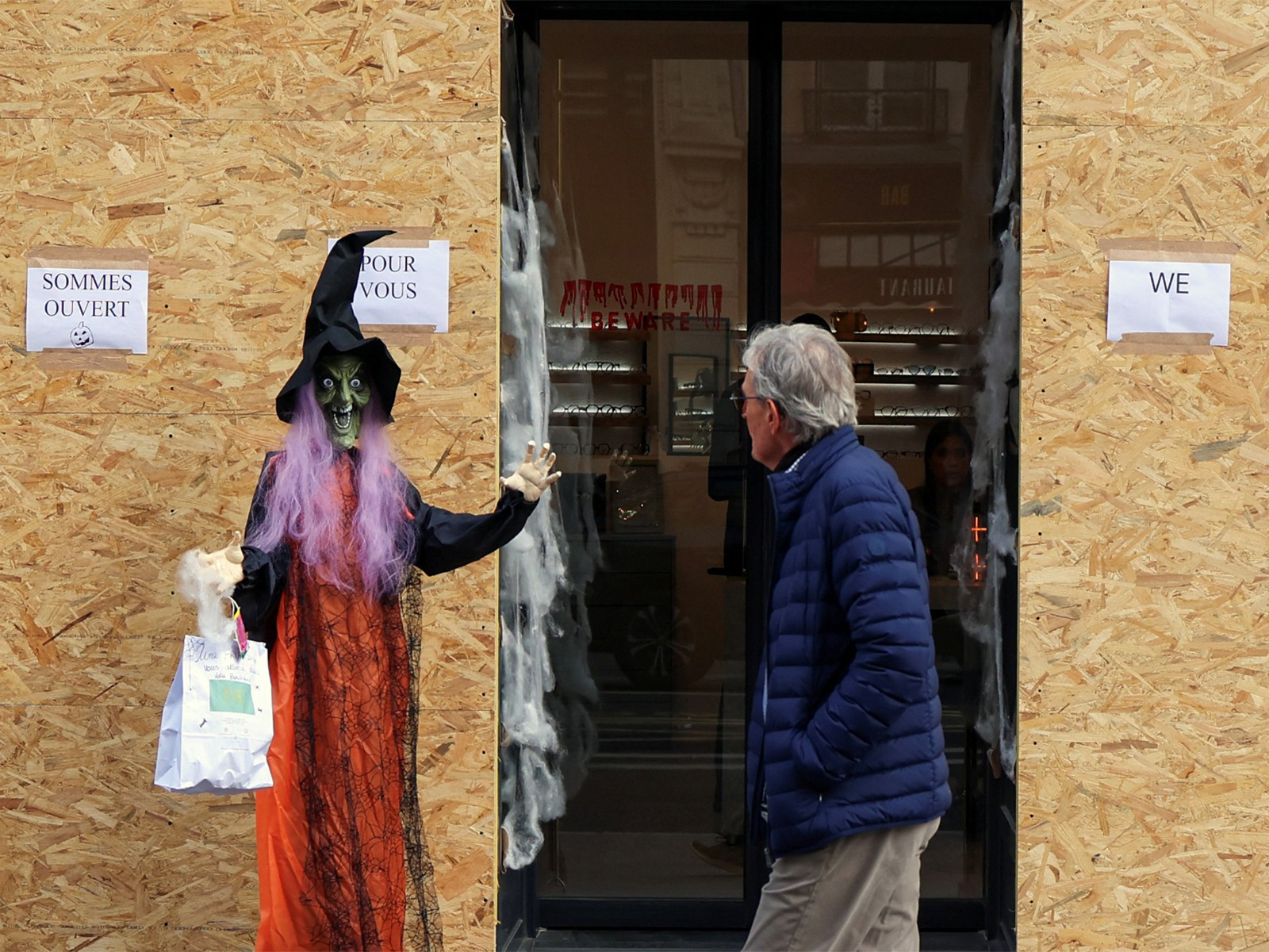 A person passes by a boarded up store with Halloween decorations following the nationwide protests against the cost of living and rising fuel prices, Paris, France (Photo/Reuters)